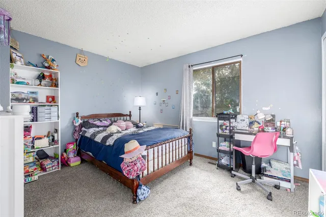 a bedroom with a bed a dresser and a large window