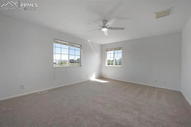 an empty room with windows and fan
