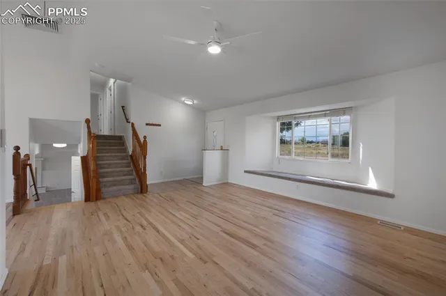 a view of empty room with wooden floor and window