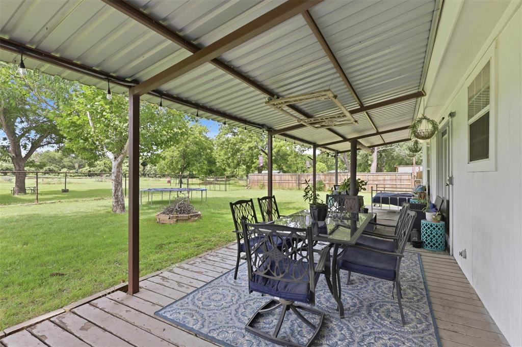 308 West 1st Street Springtown, TX 76082 - Photo 30 of 39 Expansive covered patio with a corrugated metal roof and exposed support beams