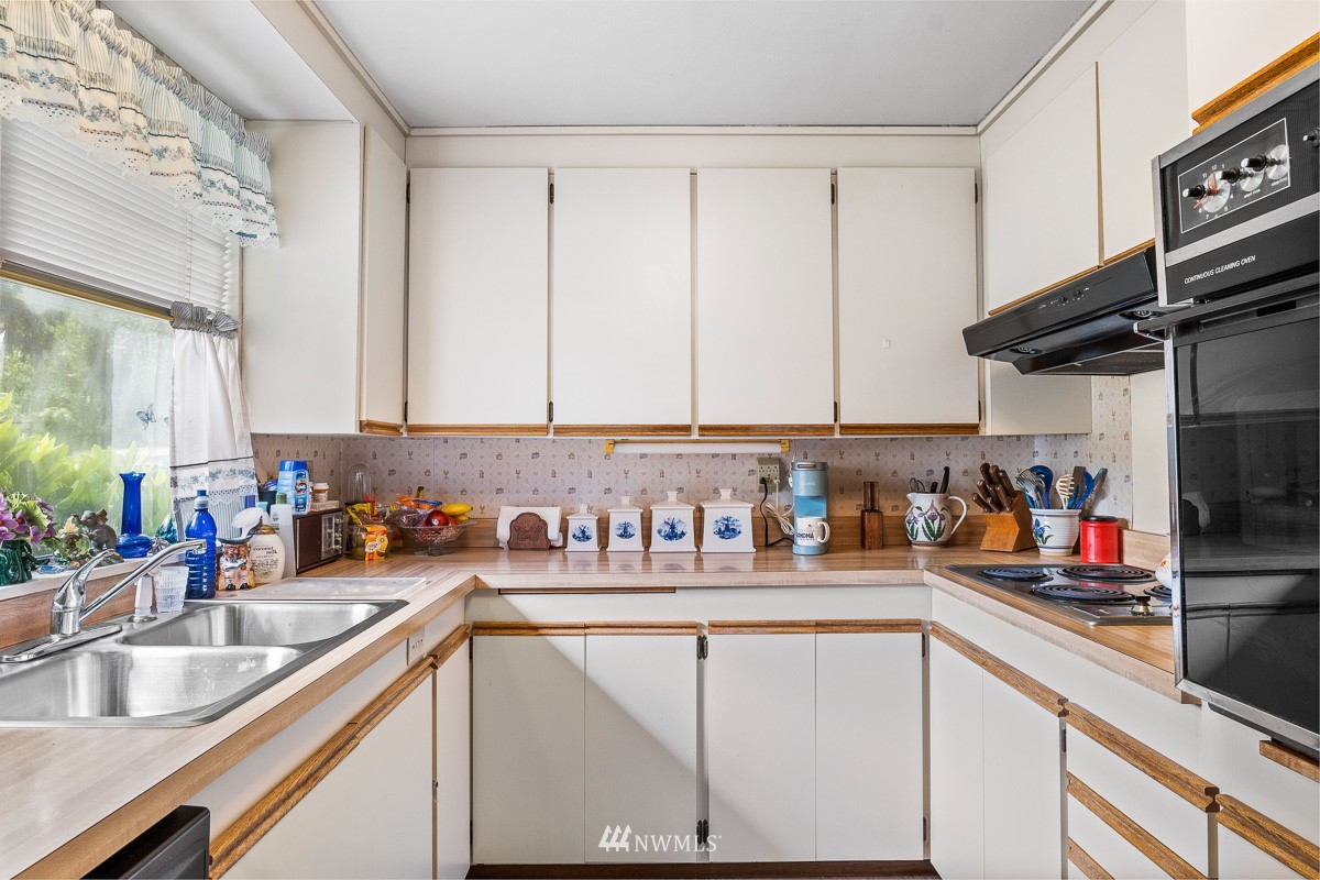 15053 Southeast 113th Street Renton, WA 98059 - Photo 16 of 31 a kitchen with stainless steel appliances granite countertop a sink dishwasher and cabinets with wooden floor