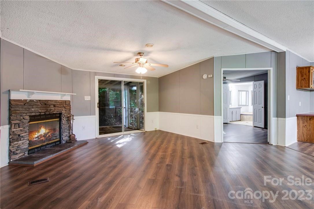 a view of an empty room with wooden floor fireplace and a window