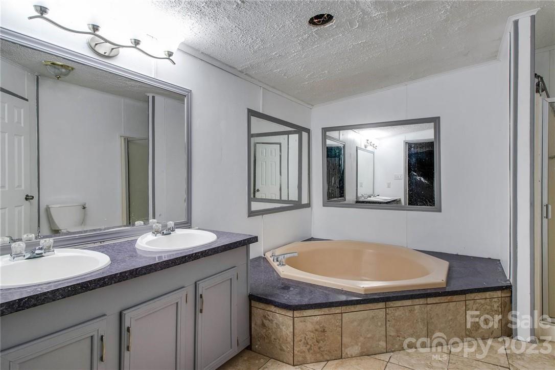 65 Hickory Nut Drive Mill Spring, NC 28756 - Photo 17 of 24 a bathroom with a granite countertop sink a mirror and bathtub