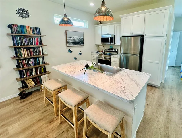 a kitchen with stainless steel appliances granite countertop a refrigerator a stove a microwave a dining table and chairs with wooden floor