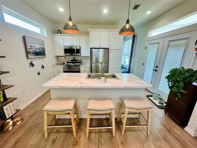 a kitchen with stainless steel appliances kitchen island granite countertop a refrigerator a stove a microwave oven a dining table and chairs with wooden floor
