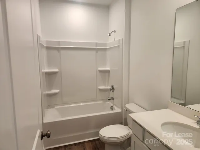 a bathroom with a granite countertop bathtub shower sink vanity and toilet