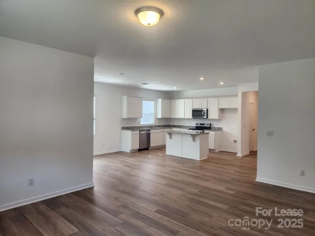 a large white kitchen with kitchen island white cabinets and stainless steel appliances