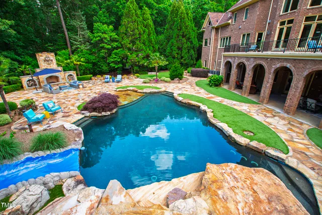 a view of a patio with couches table and chairs under an umbrella with a fireplace
