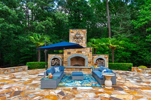 a view of a patio with couches table and chairs with potted plants and large trees
