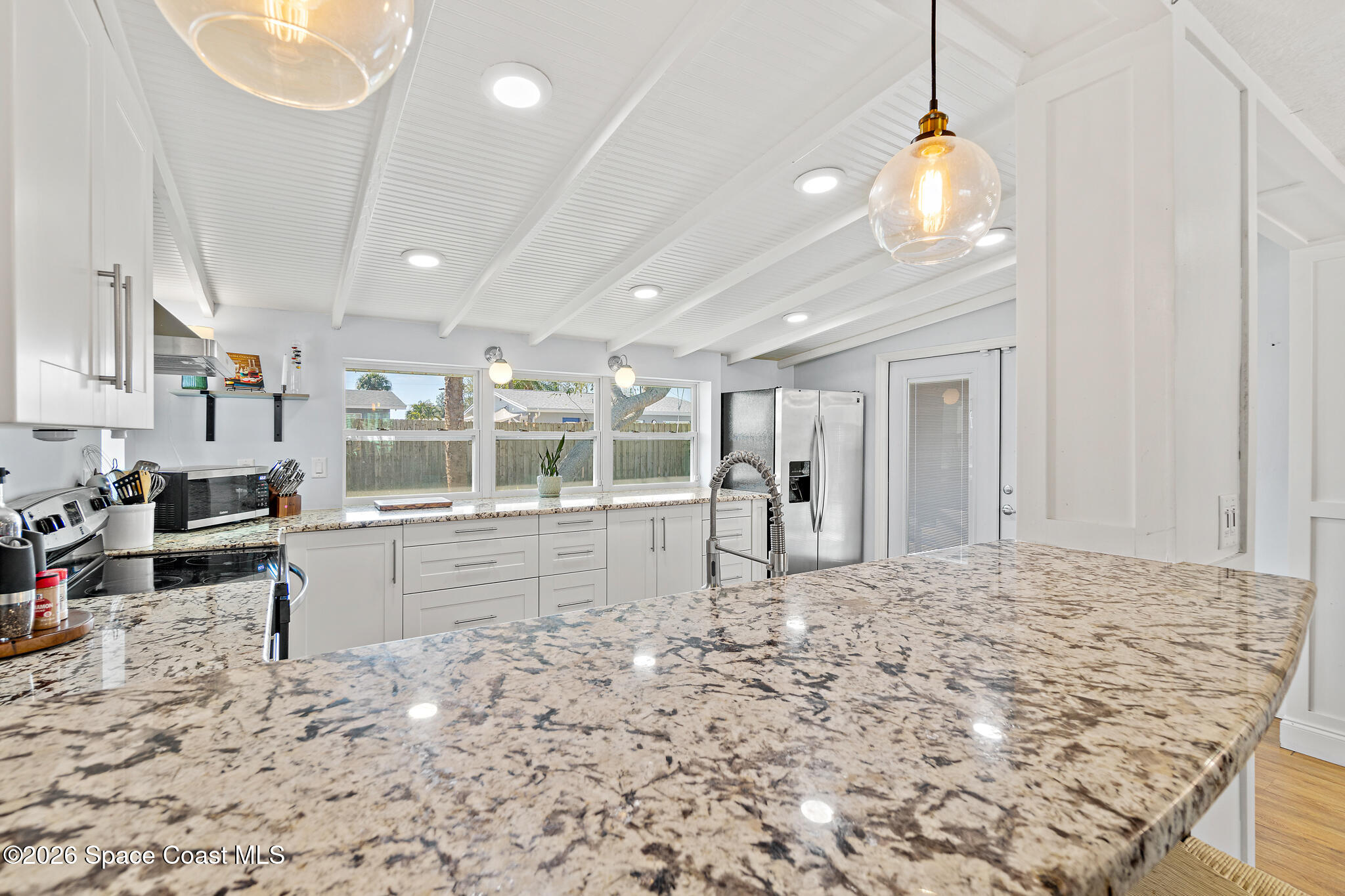 740 Java Road Cocoa Beach, FL 32931 - Photo 22 of 40 a large white kitchen with kitchen island a stove a sink and chandelier