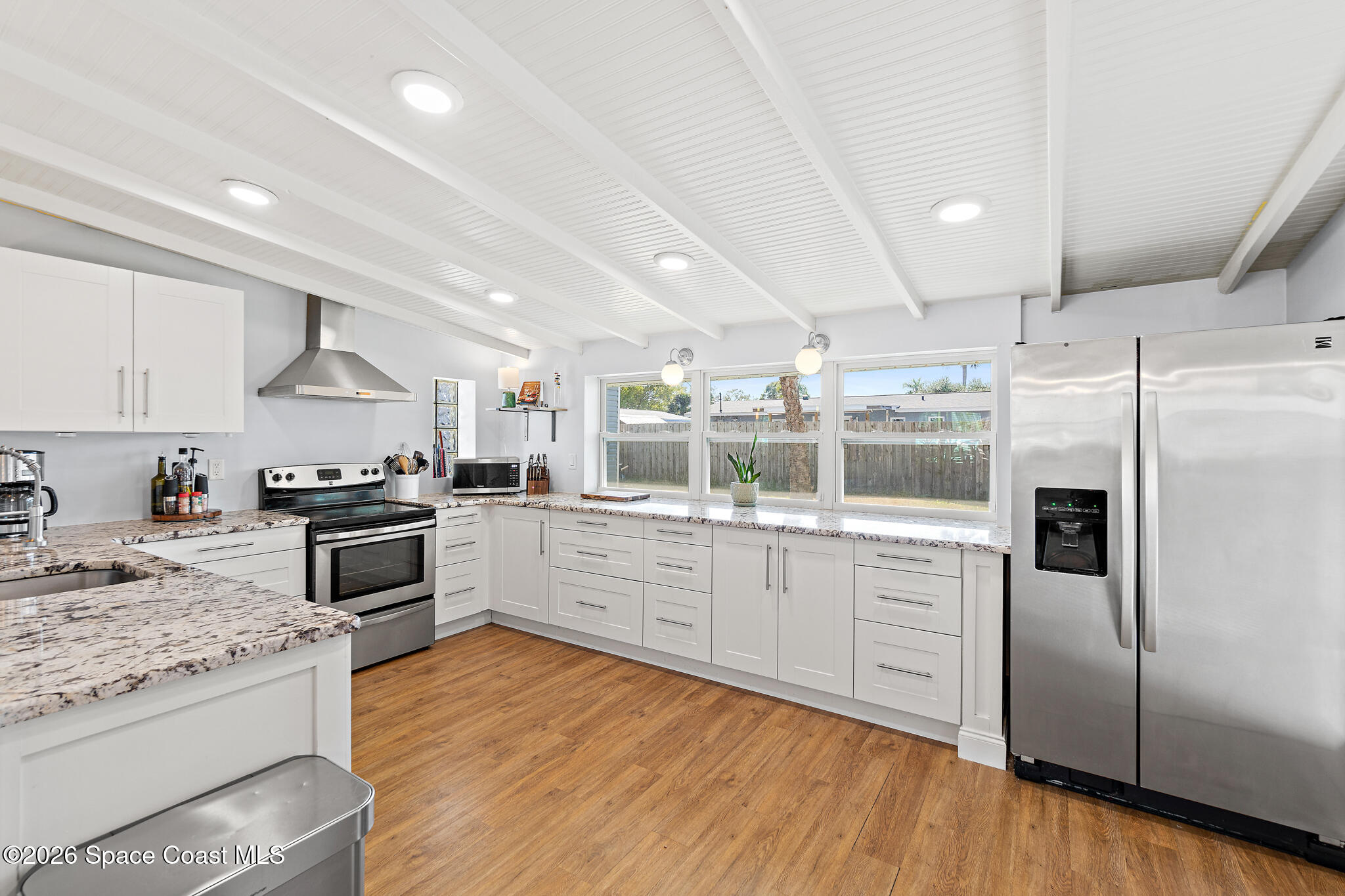 740 Java Road Cocoa Beach, FL 32931 - Photo 4 of 40 a kitchen with granite countertop a refrigerator oven a sink dishwasher and white cabinets with wooden floor