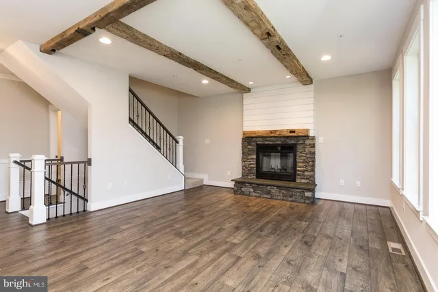 a view of an empty room with wooden floor fireplace and a window