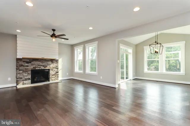 an empty room with windows a fireplace and wooden floor