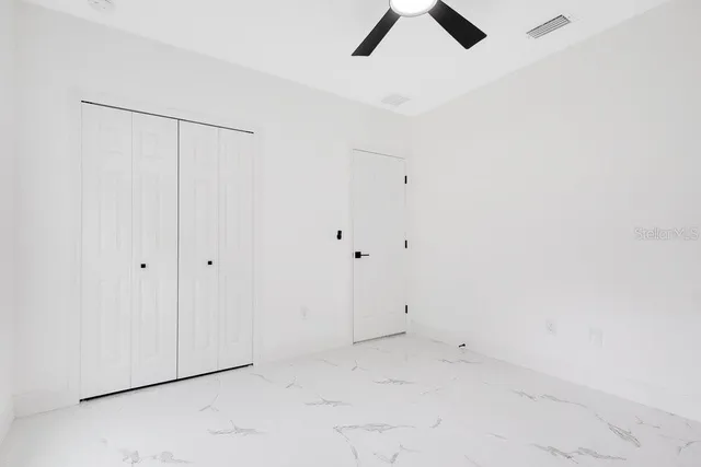 an empty room with a window and a ceiling fan