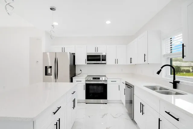 a kitchen with stainless steel appliances a refrigerator sink stove and white cabinets