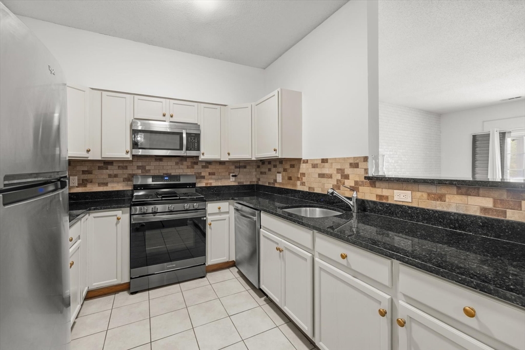 21 Hampshire Road, Unit 101 Methuen, MA 01844 - Photo 7 of 18 a kitchen with granite countertop a sink and a stove top oven