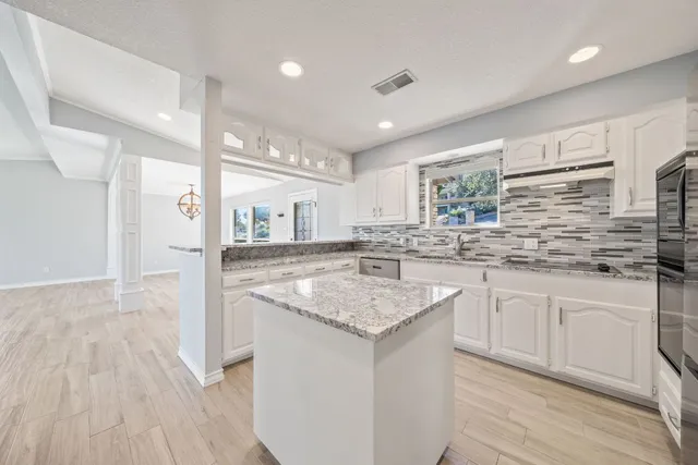 a kitchen with granite countertop a sink and cabinets with wooden floor