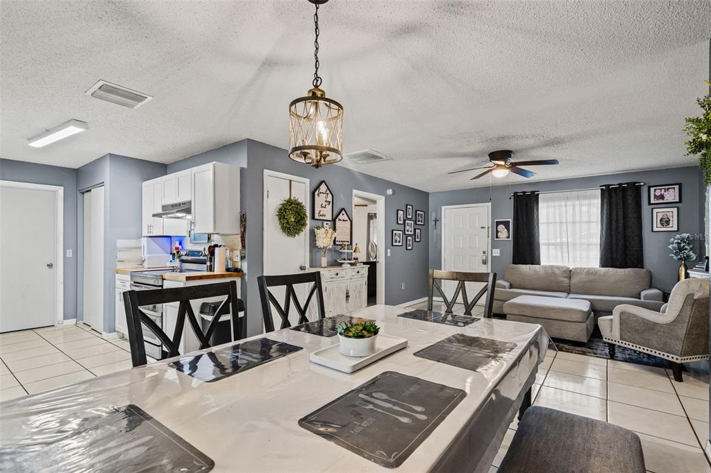 12989 Linden Drive Spring Hill, FL 34609 - Photo 13 of 28 a view of a dining room and livingroom with furniture wooden floor a rug a flat screen tv a rug and a chandelier