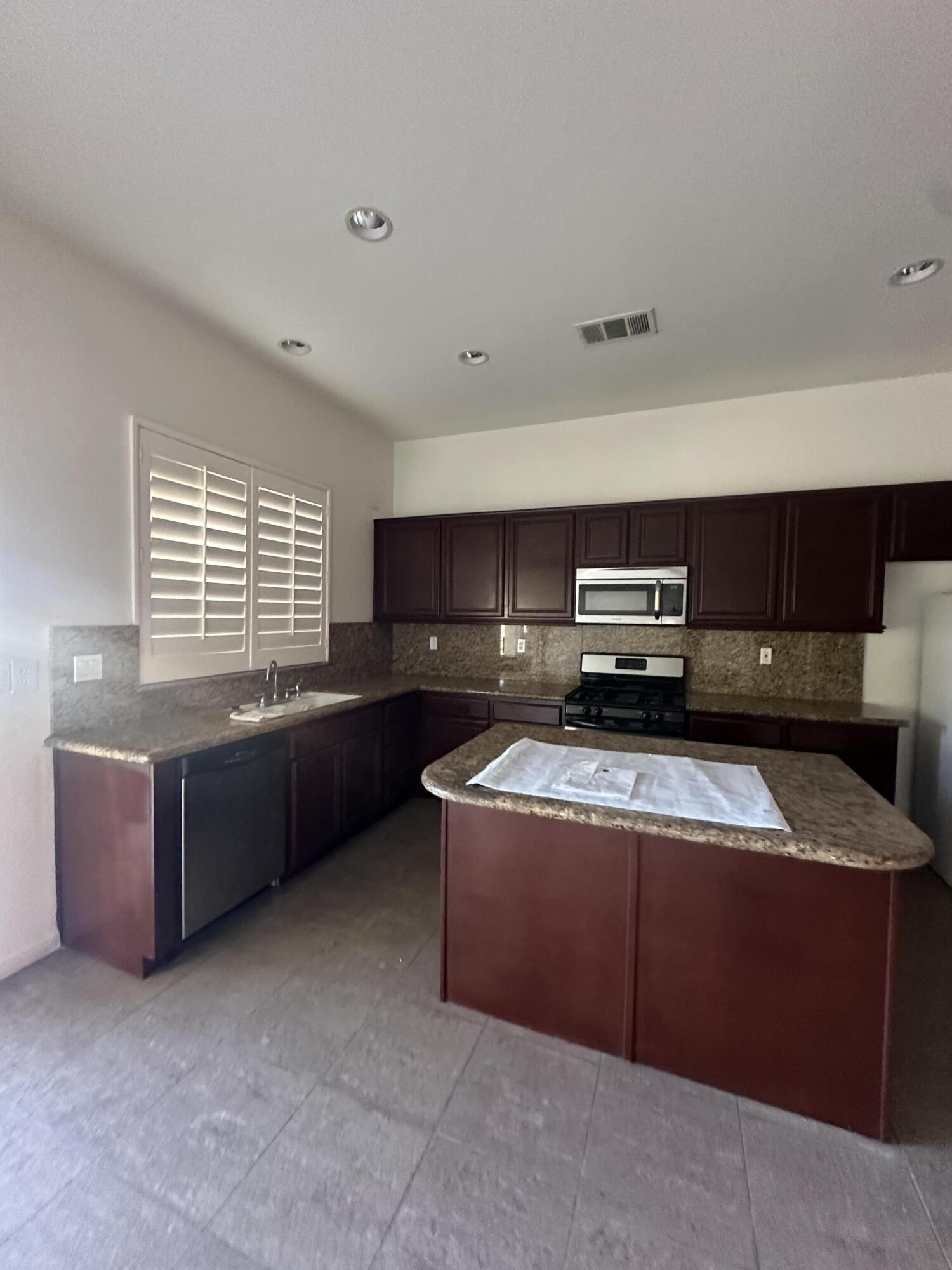 a kitchen with stainless steel appliances kitchen island granite countertop a stove a sink and a microwave