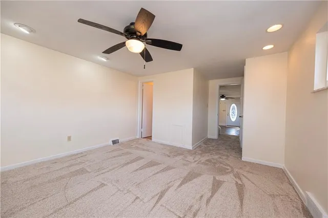 a view of a room with a ceiling fan and hardwood floor