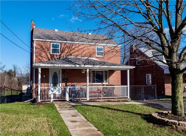 a view of house with a big yard and large tree