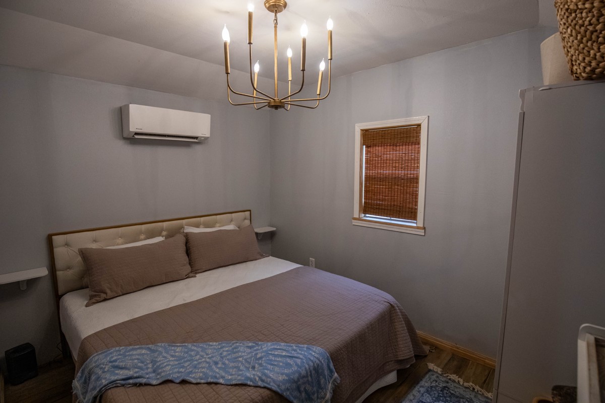 143 Harrison Road Beeville, TX 78102 - Photo 10 of 39 Bedroom featuring a wall unit AC, wood finished floors, and a chandelier