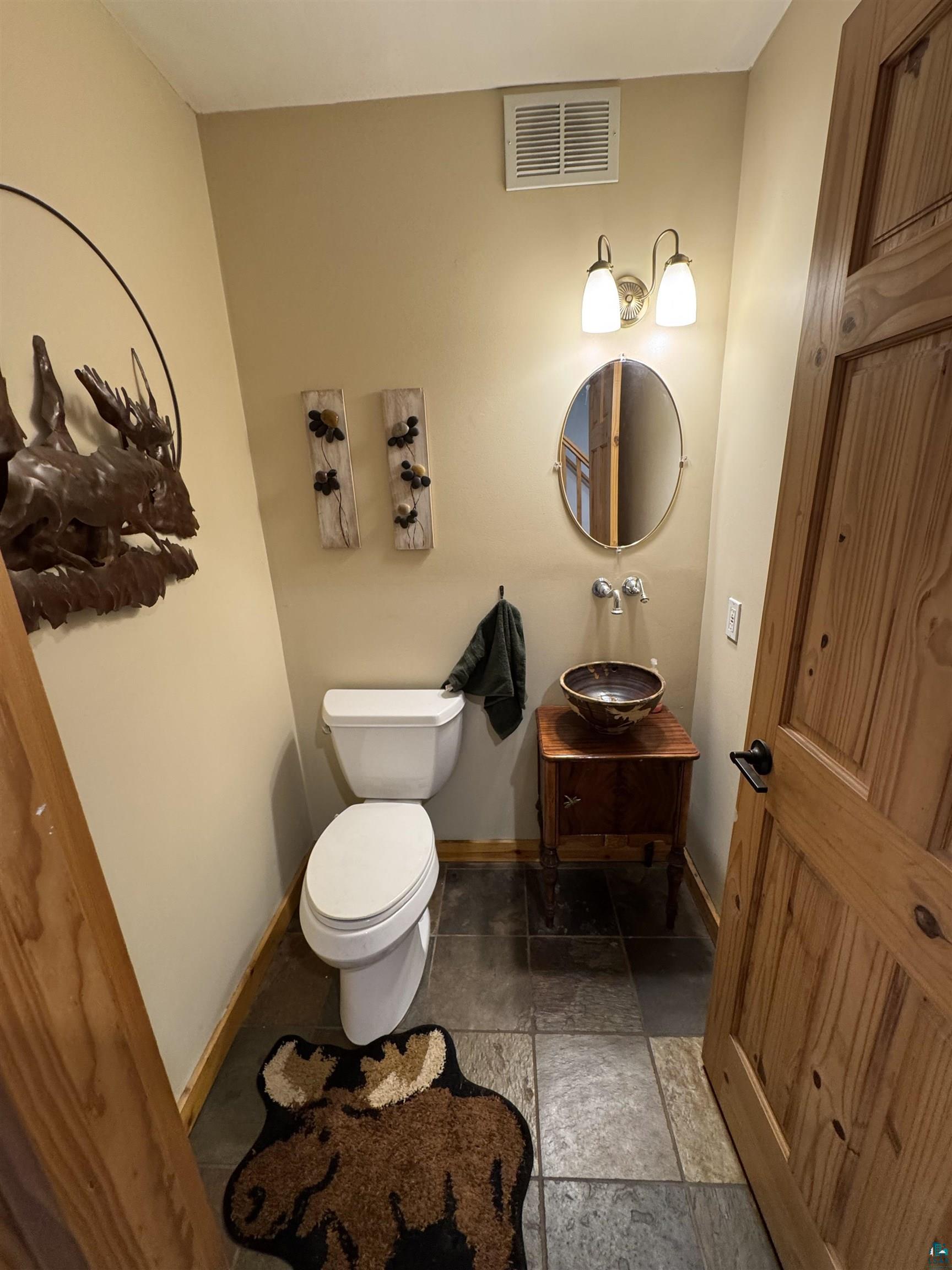 1745 Becks Road Maple, WI 54854 - Photo 11 of 46 Powder room featuring a white toilet, stone tile flooring, and a vanity with a vessel sink