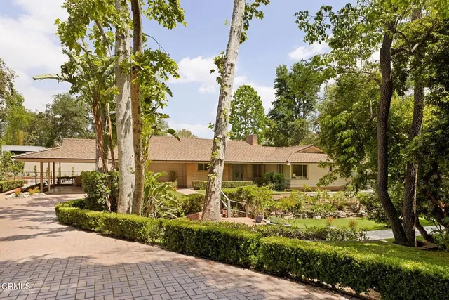 a view of a white house with a big yard and large trees