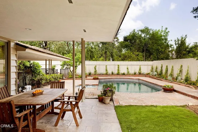 a view of a swimming pool with chairs and table in patio