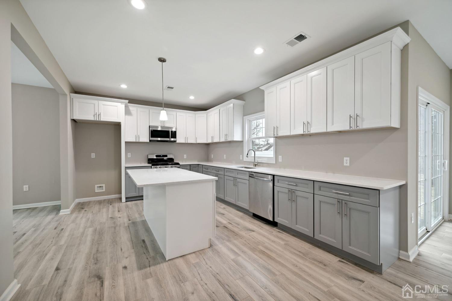 66 Runyon Avenue Edison, NJ 08817 - Photo 15 of 34 a kitchen with wooden floors white cabinets and stainless steel appliances