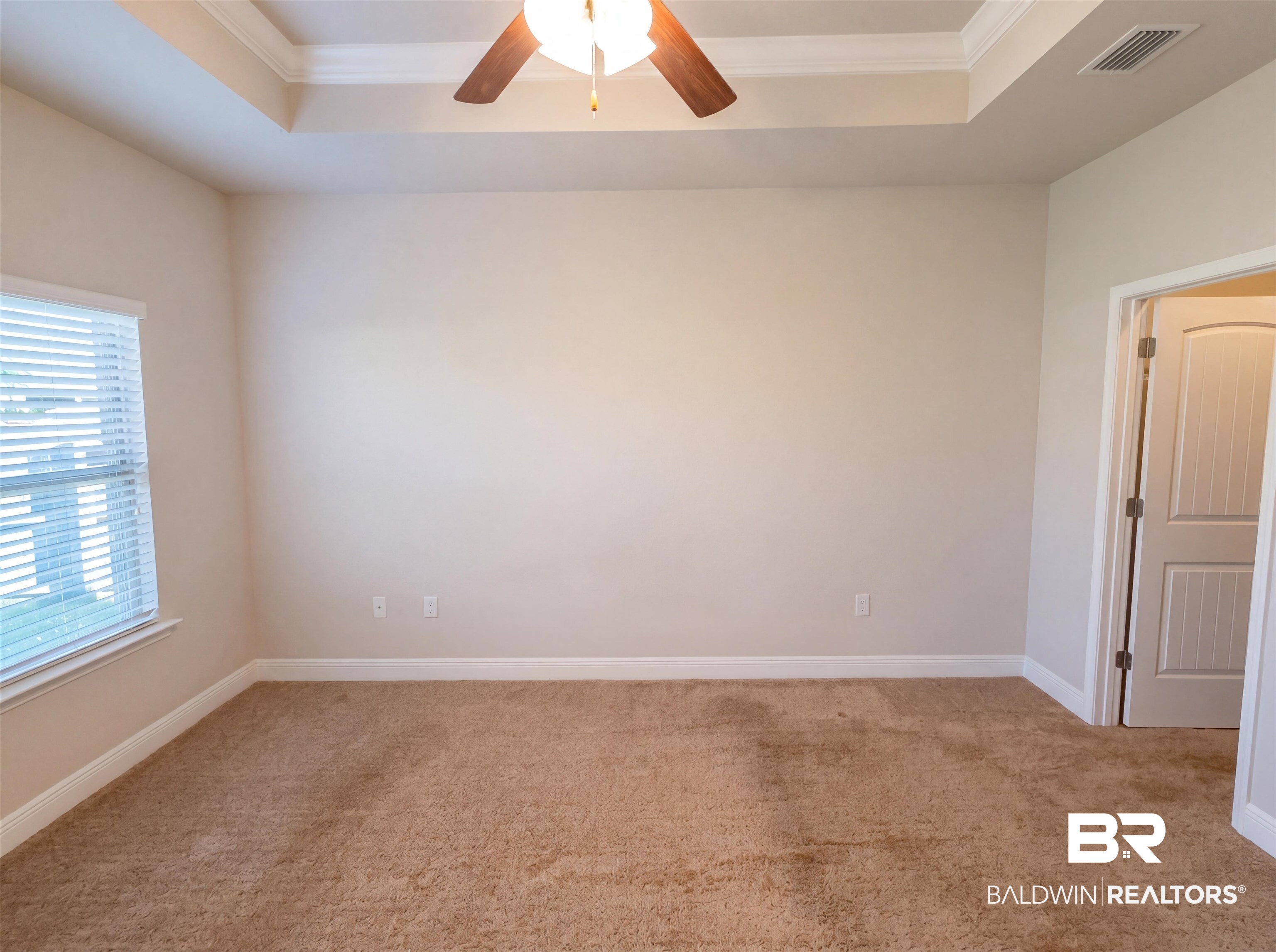 1740 Covington Lane Foley, AL 36535 - Photo 4 of 18 Spacious room featuring a tray ceiling with crown molding, a ceiling fan, a window with horizontal blinds, and a paneled interior door