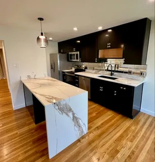 a large kitchen with stainless steel appliances kitchen island granite countertop a table and chairs