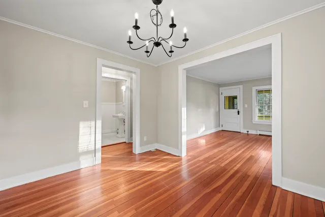 a view of an empty room with wooden floor and a chandelier