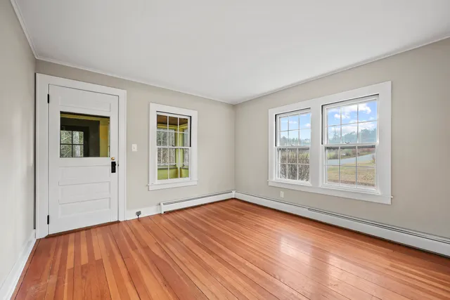 a view of an empty room with wooden floor and a window