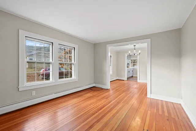 a view of an empty room with wooden floor and a window