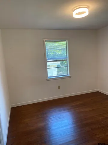an empty room with wooden floor and a window