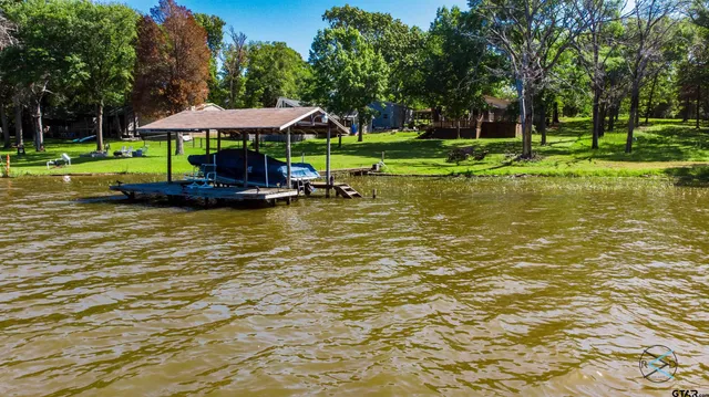 a view of a lake with a table and chairs under an umbrella