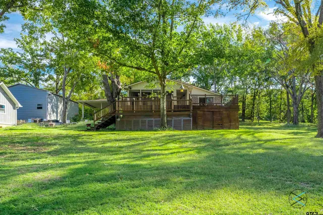 a big yard with wooden fence and large trees