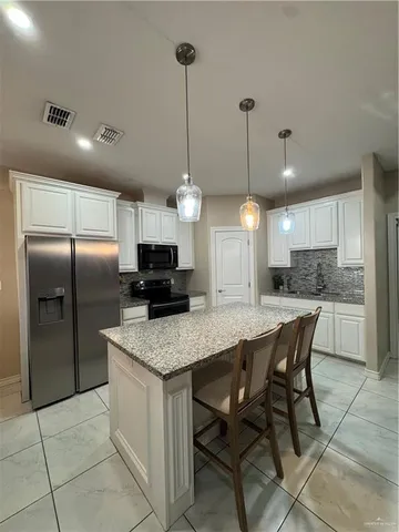 a kitchen with stainless steel appliances granite countertop a sink a stove a refrigerator a center island a refrigerator and a counter top