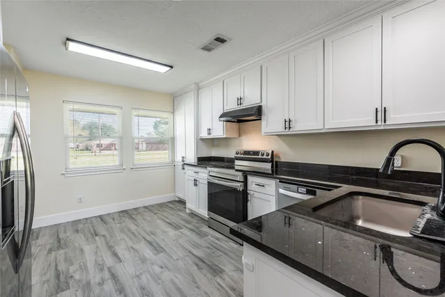 a kitchen with granite countertop a stove a sink and a refrigerator