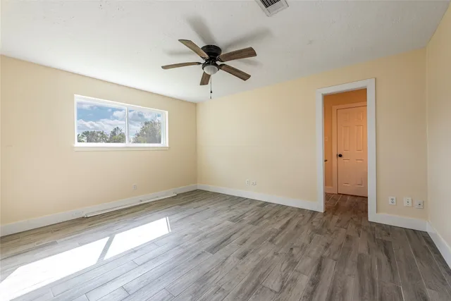 a view of an empty room with wooden floor and a window