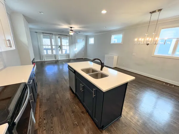 a kitchen that has a sink a microwave oven a stove and white cabinets with wooden floor