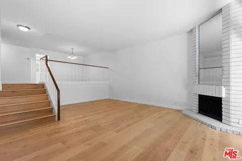 a view of empty room with wooden floor and fireplace