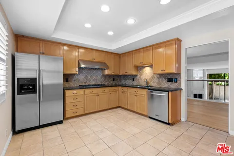 a kitchen with stainless steel appliances granite countertop a refrigerator a sink and a stove