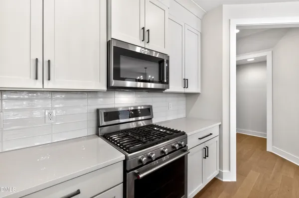 a kitchen with stainless steel appliances white cabinets and a stove top oven
