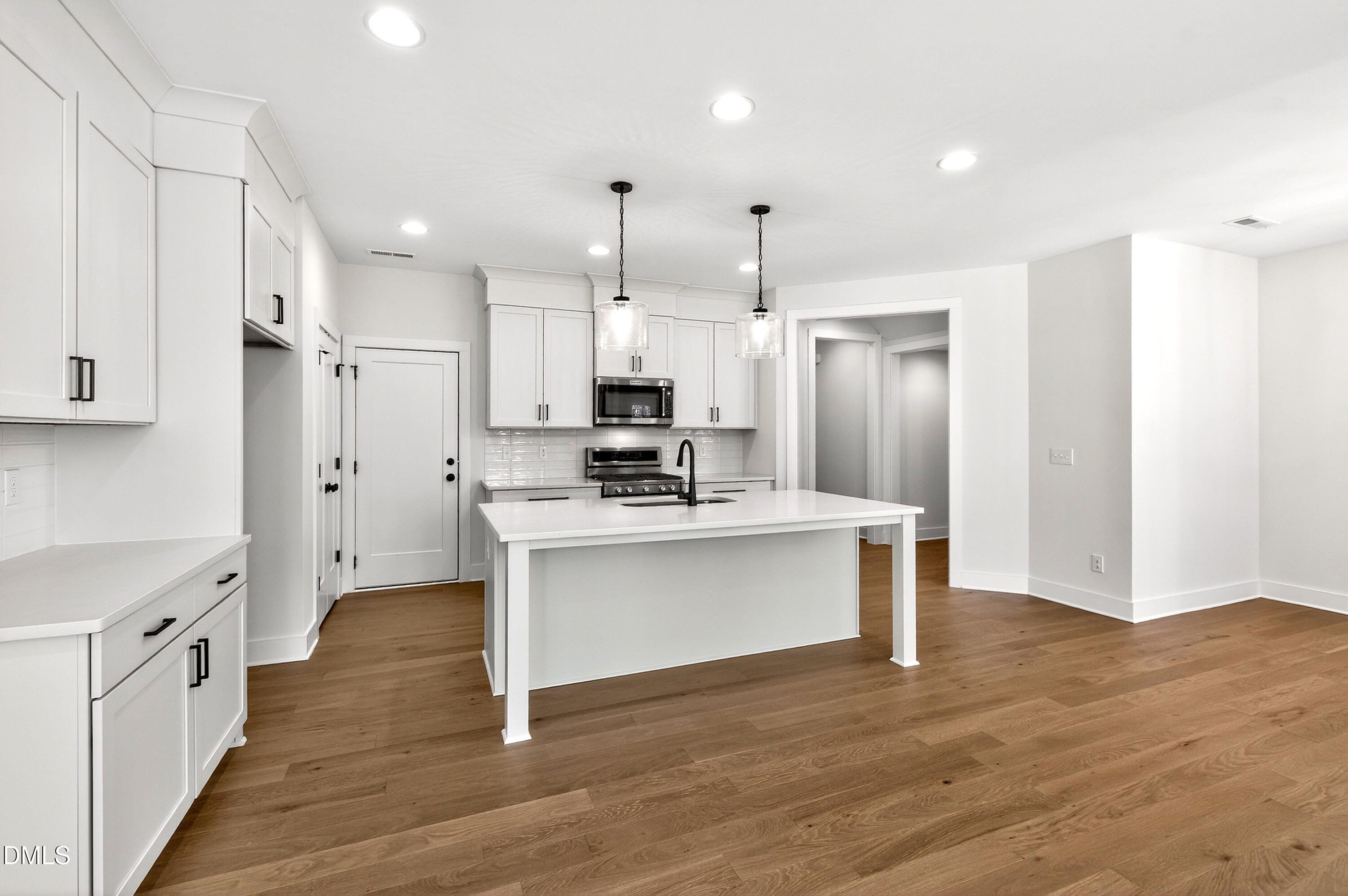 976 Double Helix Road Apex, NC 27523 - Photo 15 of 50 a large kitchen with a center island wooden floor stainless steel appliances and cabinets