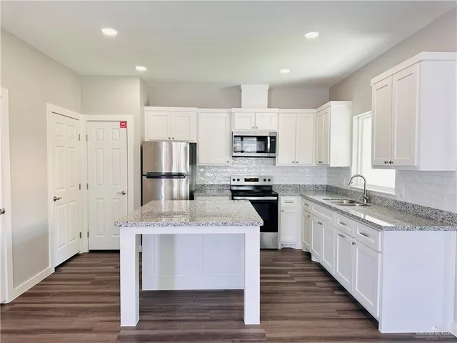 a large kitchen with stainless steel appliances granite countertop a lot of counter space and wooden floors