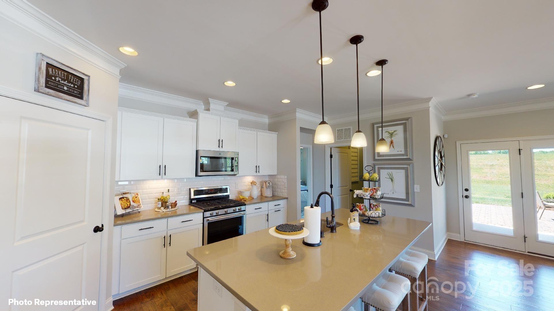 112 Noah Lane Troutman, NC 28166 - Photo 2 of 27 a kitchen with a refrigerator a stove a sink a dining table and chairs with wooden floor