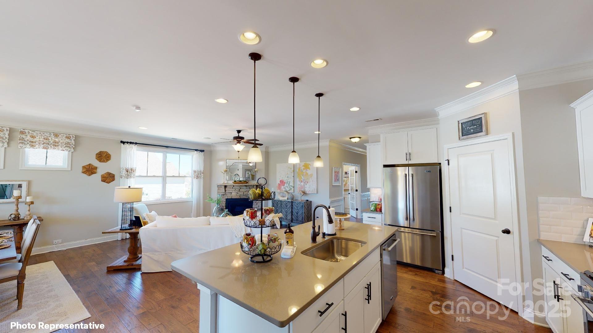 112 Noah Lane Troutman, NC 28166 - Photo 4 of 27 a kitchen with stainless steel appliances kitchen island granite countertop a refrigerator a sink a dining table and chairs with wooden floor