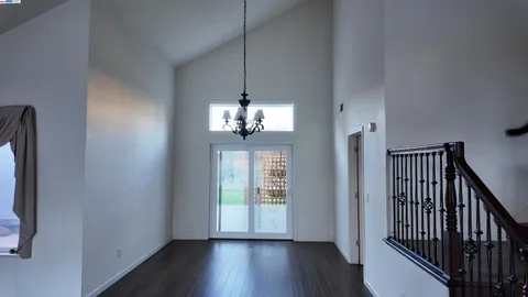 a view of a hallway with wooden floor and chandelier